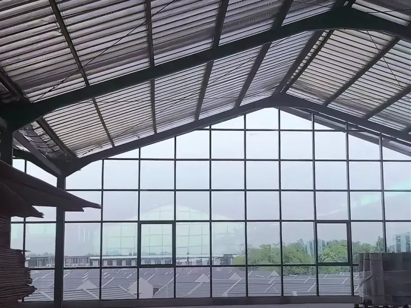 Curtain wall aluminium dan kaca pada sisi bangunan berangka baja yang dipasang NCA