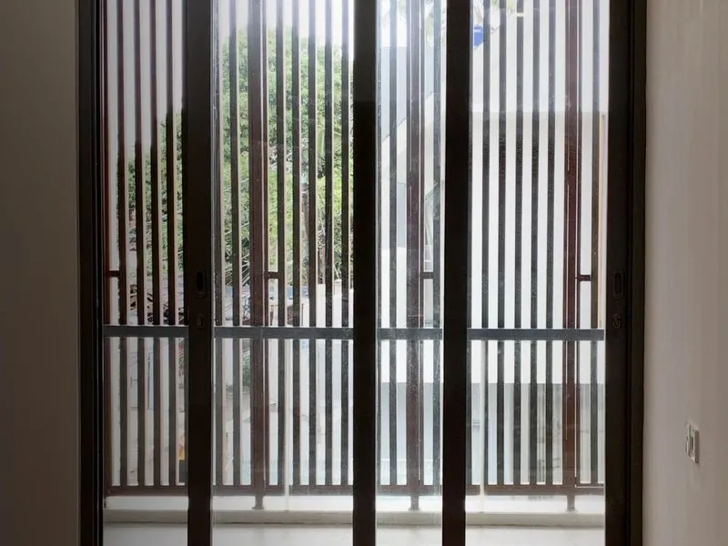 Pintu geser aluminium hitam ke balkon dengan kisi vertikal